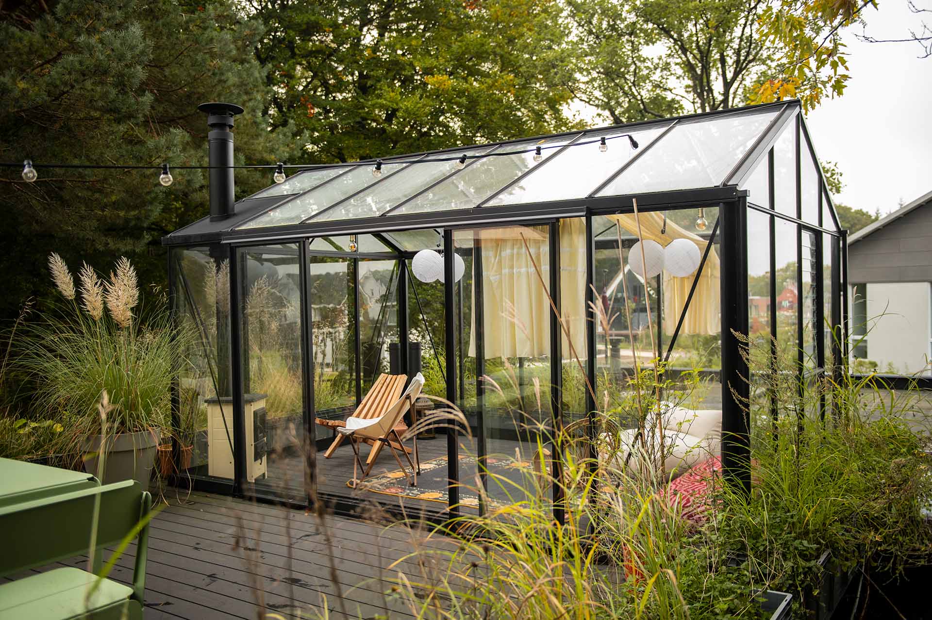 Impressie van een tuinkas met glazen wanden, dak en zwart profielen van aluminium.